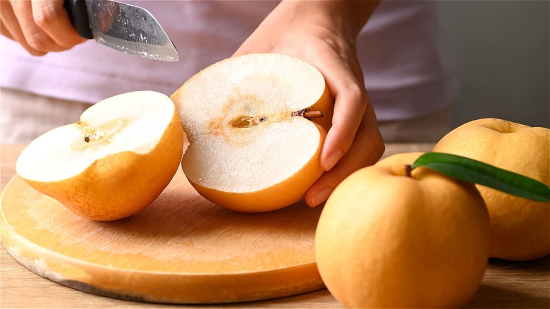 Hands with knife cutting Asian pear 