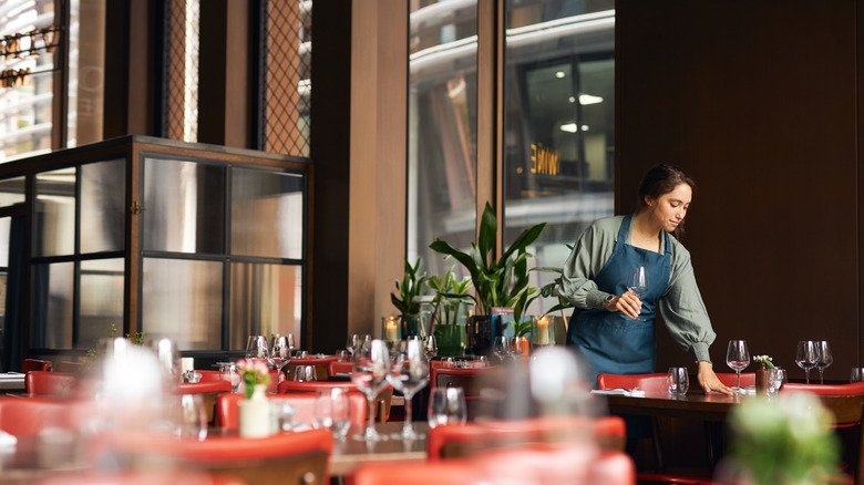 Person setting tables at restaurant