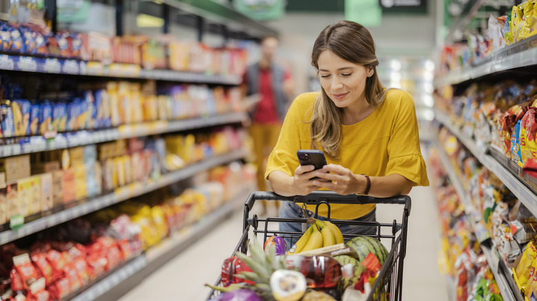 Woman grocery shopping looking at phone