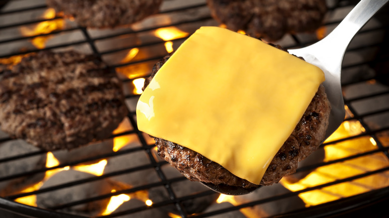 Person placing cheese slices on burgers