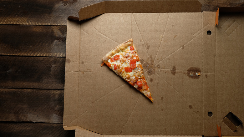 a single slice of pizza sitting inside an open pizza box