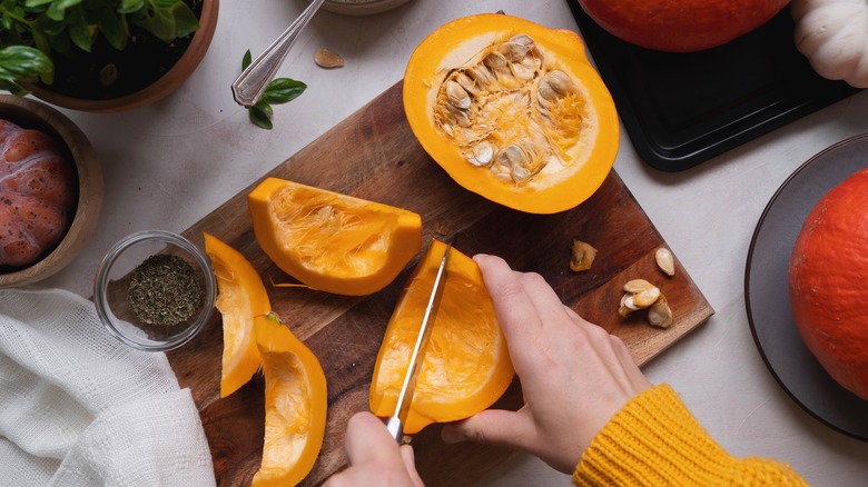 Hands slicing pumpkin