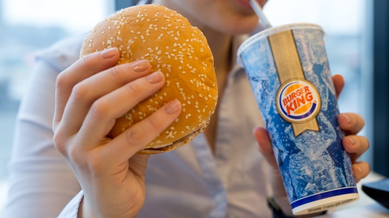 woman holding hamburger and soda