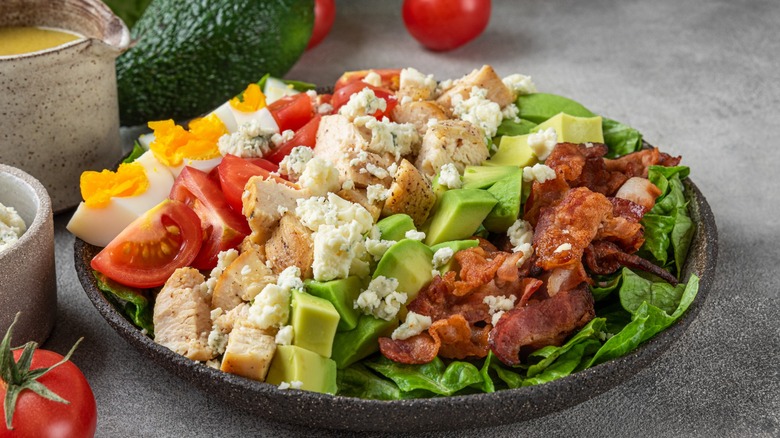 Cobb salad on plate by tomatoes and avocado