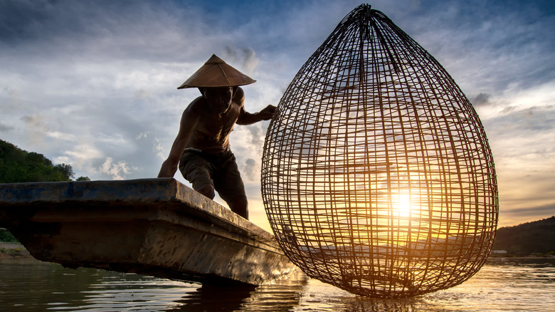 Fisherman on the Mekong River, with a reed fishing basket