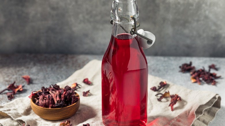 Bottle of red liquid with hibiscus leaves