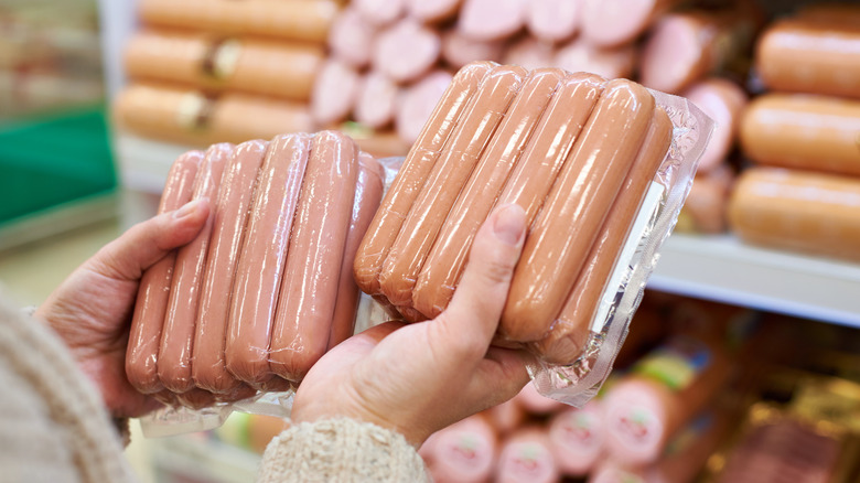 Person holding raw hot dogs at store