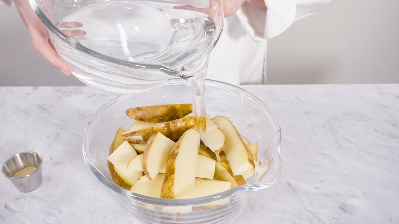 Pouring water onto sliced potatoes