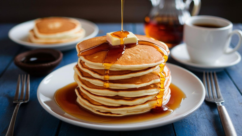 Generous stack of pancakes topped with butter and syrup