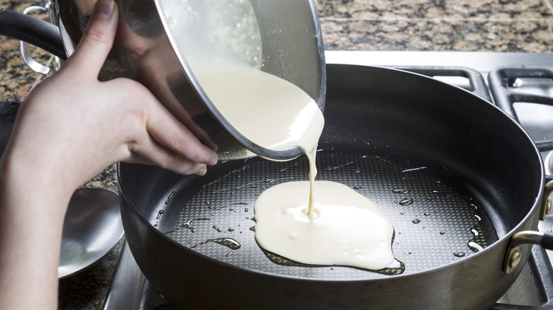 Pouring pancake batter onto a heated and oiled pan