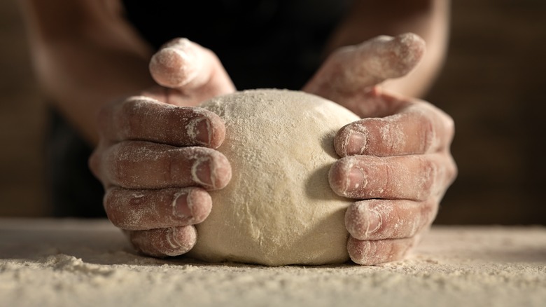 shaping ball of dough with flour