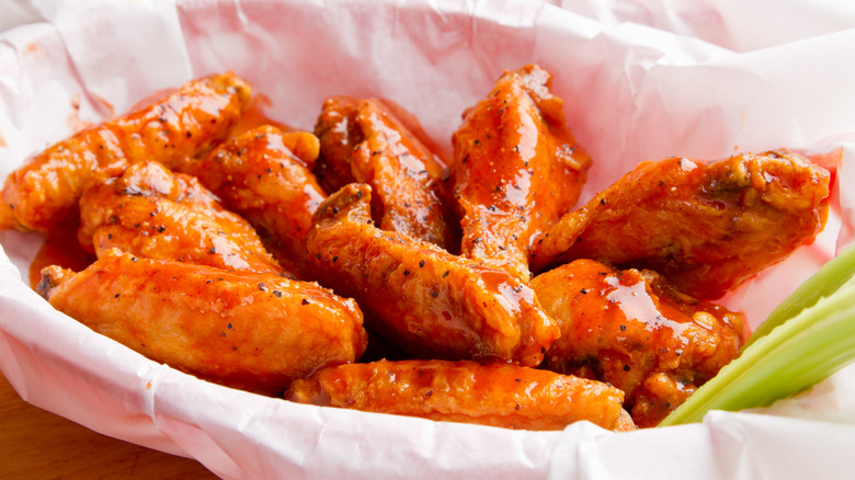 Basket of hot and spicy chicken wings with a celery stick