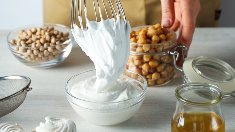 Person whisking a bowl of fluffy aquafaba meringue