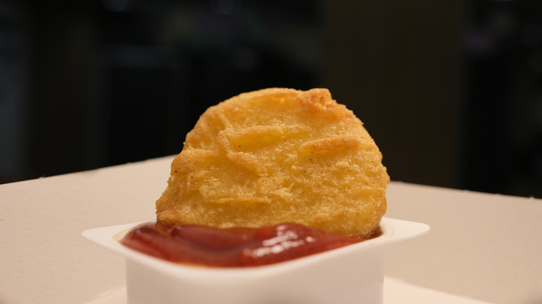 A single Chicken McNugget dipped in ketchup