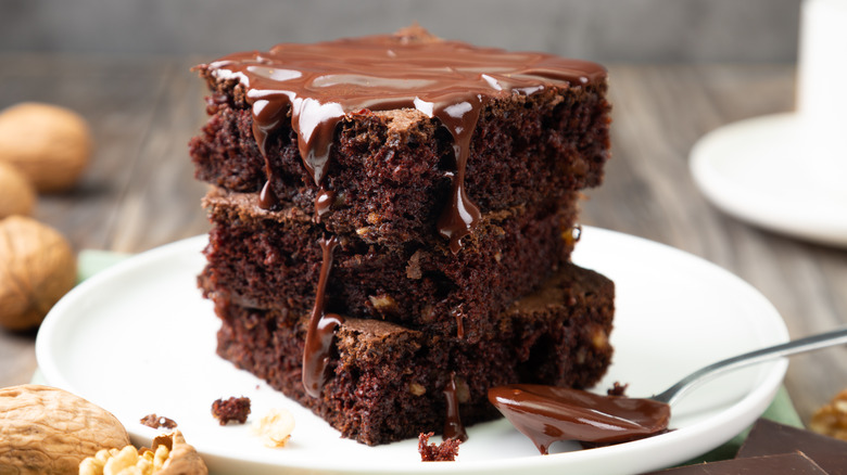 pile of gooey frosted brownies on white plate