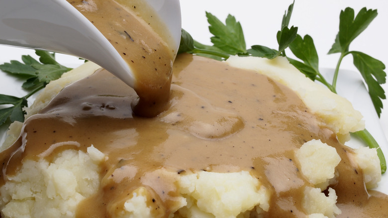 Pouring gravy on mashed potatoes
