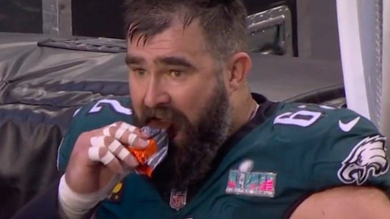 Jason Kelce eating a candy bar on the sidelines