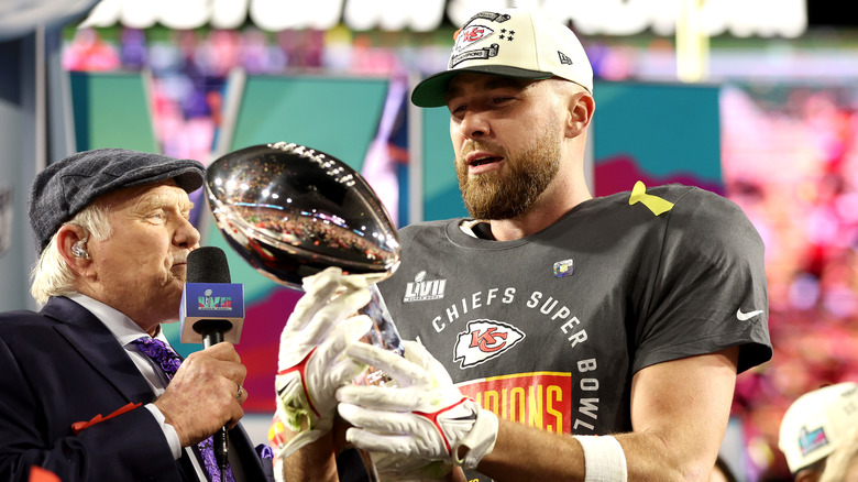 Travis Kelce holds the Vince Lombardi Trophy as Terry Bradshaw looks on