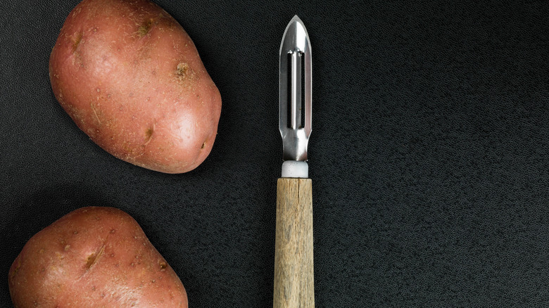 Potatoes next to a swivel potato peeler 