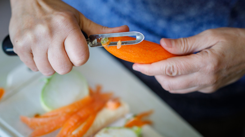 Hands peeling carrots with peeler