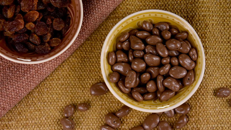 Bowl of chocolate covered raisins on a brown cloth