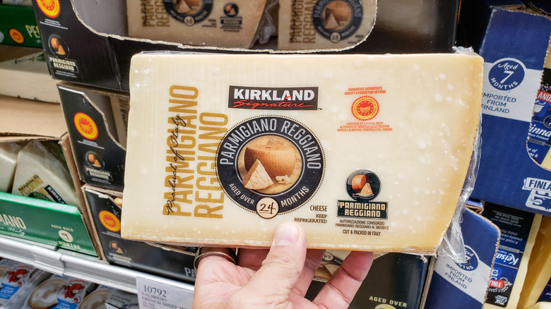 A person holds a block of Kirkland Parmigiano-Reggiano