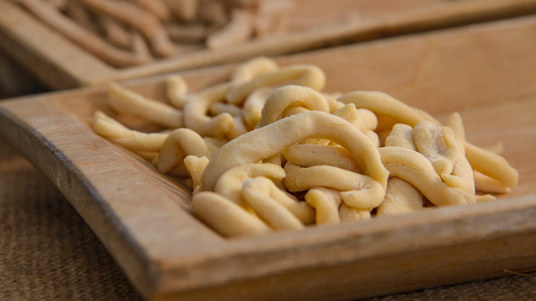 Handmade strozzapreti noodles in a wooden dish