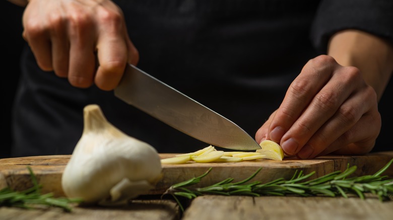 A chef's hands chopping garlic