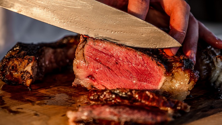 Knife slicing perfectly cooked steak