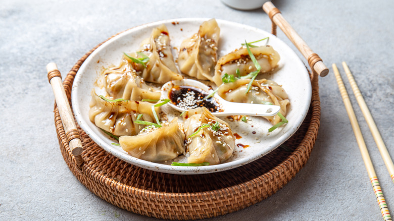 Jiaozi dumplings on white plate, gray background.