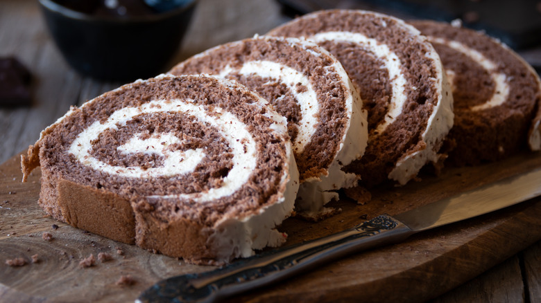 chocolate roulade with vanilla filling sliced on wooden board