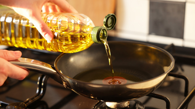 person pouring oil into pan