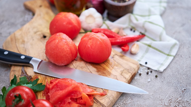 peeled tomatoes sitting on a cutting board next to knife