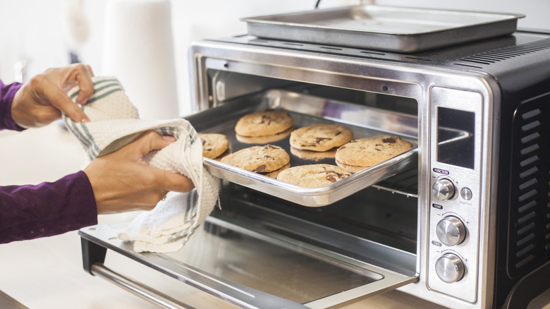 Cook removing cookies from toaster oven