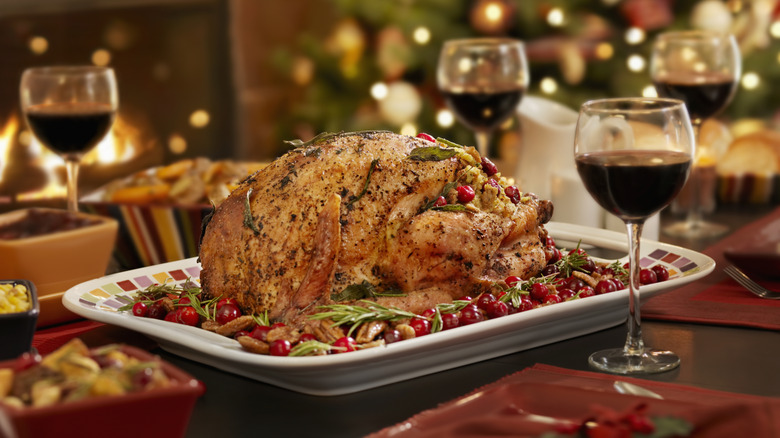 Whole turkey on a festive table with a Christmas tree in the background