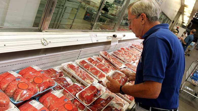 A Costco customer reads labels on meat