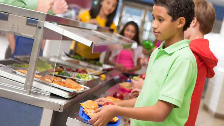 Kids getting school lunch in cafeteria.