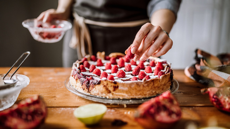 Person setting fresh strawberries atop a bake pie or cake