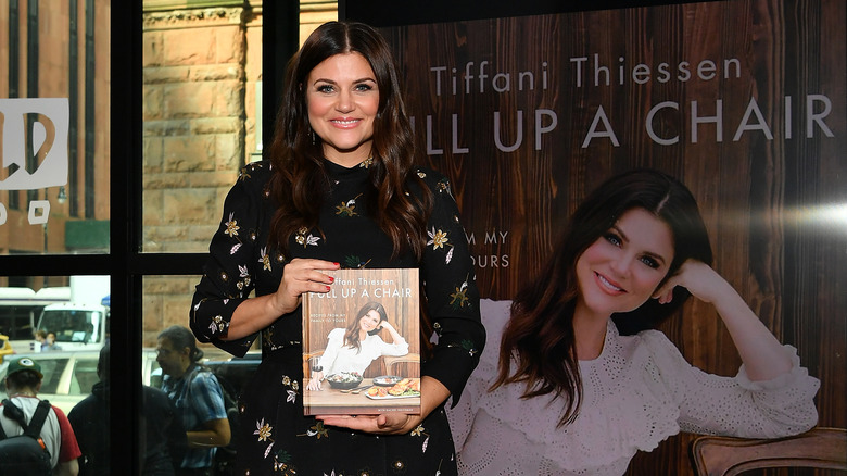 Tiffani Thiessen posing with her cookbook