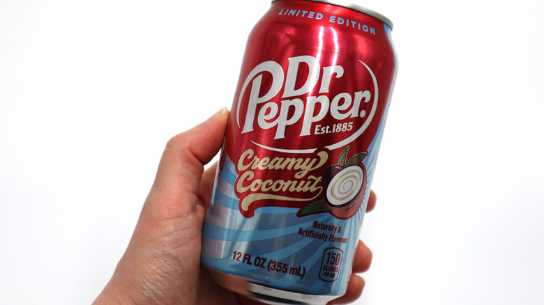 A hand holding a can of dr pepper creamy coconut