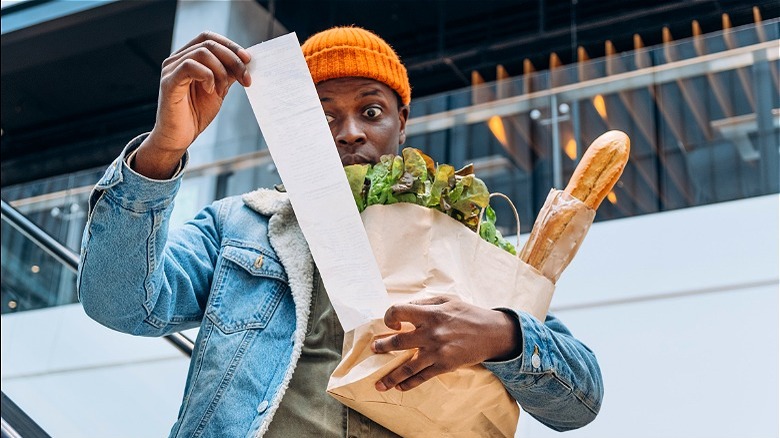 Man with groceries reading receipt