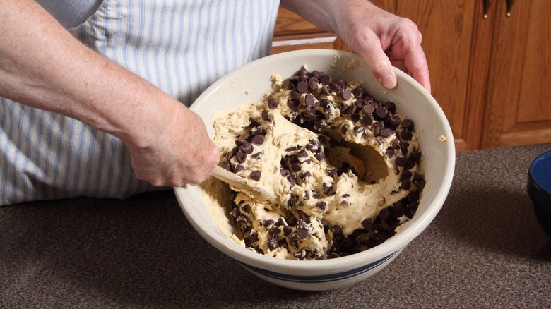 mixing raw chocolate chip cookie dough in a bowl