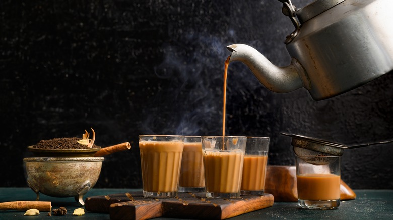 chai tea poured into glasses with tea leaves and cardamom