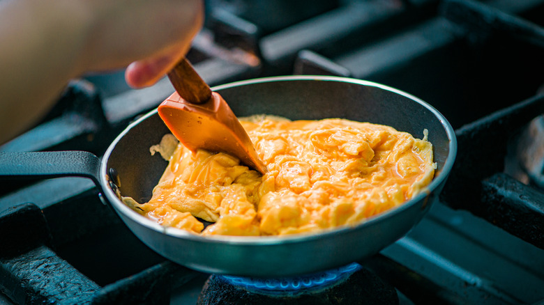 A person cooks scrambled eggs