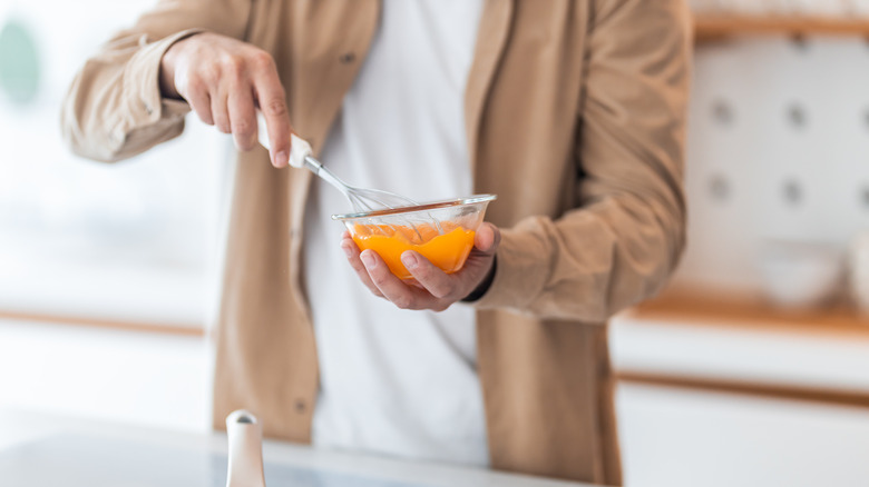 A person whisks eggs in a bowl