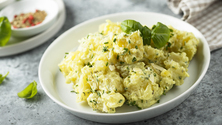 Yellow potato salad with chives on white plate