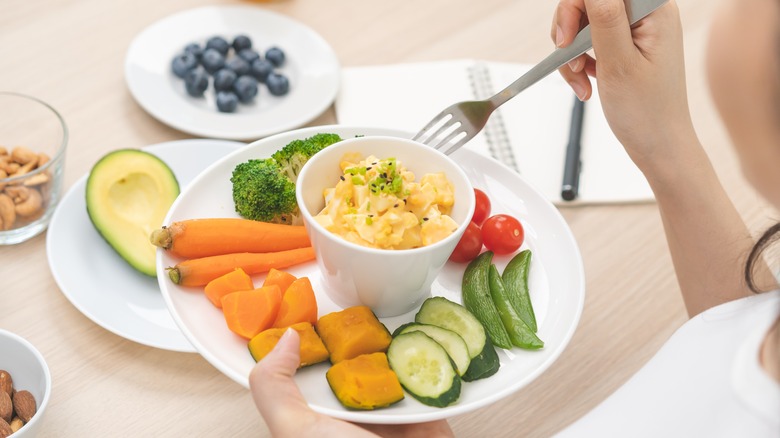 Woman eating egg sa;ad with veggies