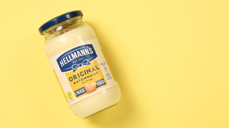 A jar of Hellmann's mayonnaise on a yellow background