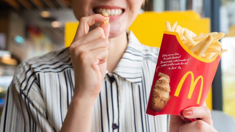 smiling person holding McDonald's French fries carton