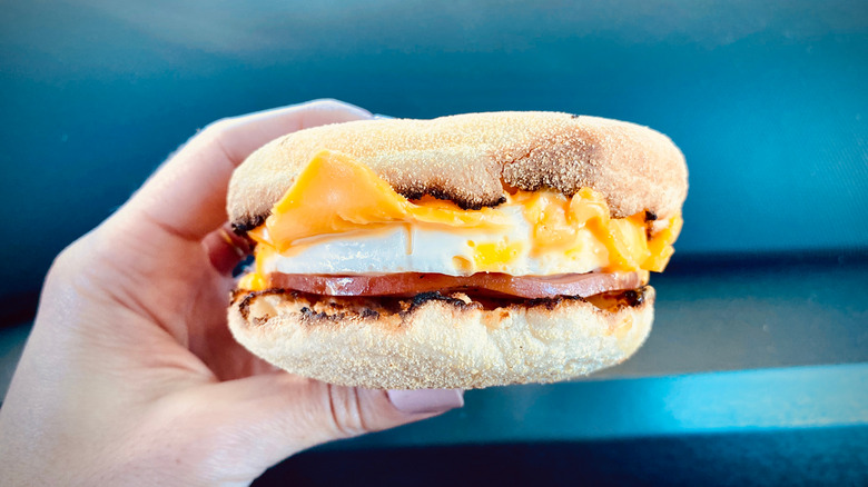 Person holding an egg ham and cheese McMuffin